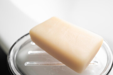 Diagonally placed a beige-colored bar of soap on the transparent saucer