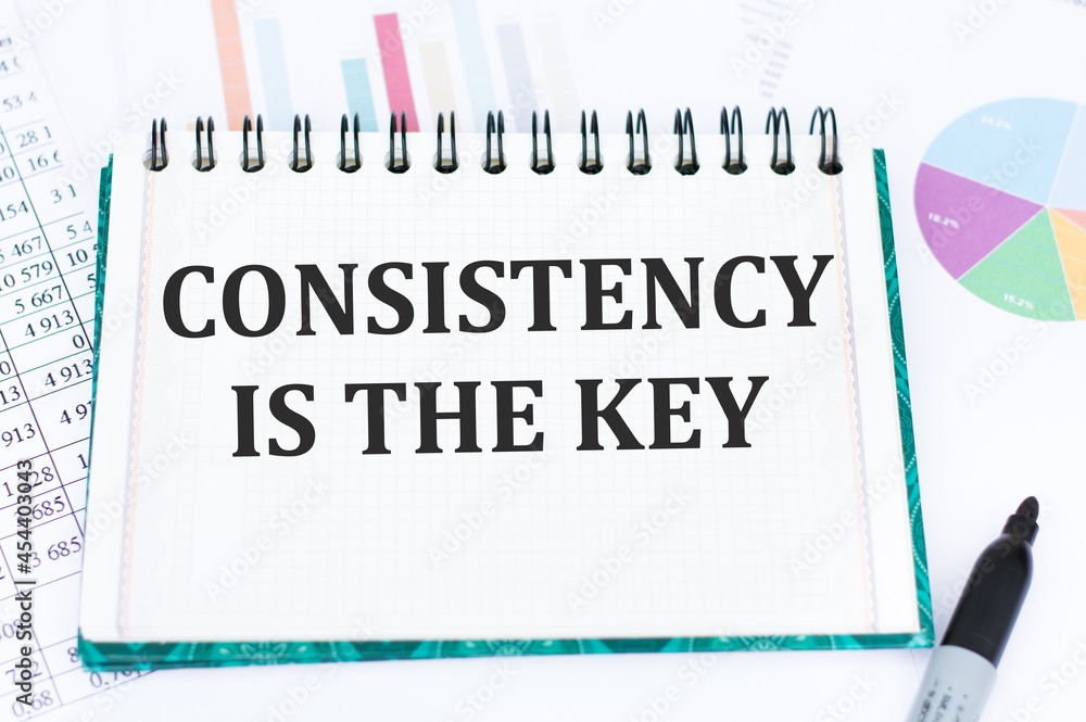 Aufkleber consistency is key text on a notebook against the background of financial charts
