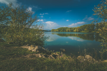 Fototapeta na wymiar scenic pond with trees around in autumnal atmosphere