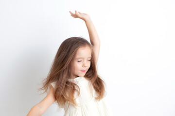 Fototapeta na wymiar A sweet gentle girl dances with her eyes closed. Happiness, inspiration. White background, space for text.