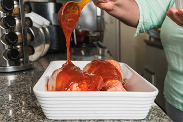 Close-up view of a woman spreading sauce on turkey legs
