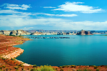Naklejka na ściany i meble View on tranquil lake with dry arid landscape against blue summer sky with clouds - Lake Mead, USA