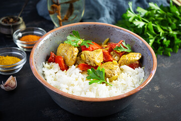 Spicy chicken curry with rice. Curry sauce with chicken and rice on dark background