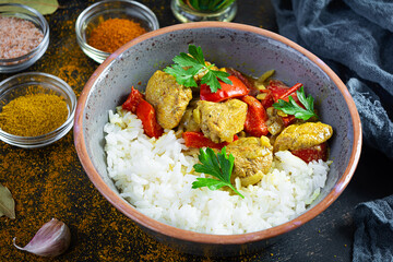Spicy chicken curry with rice. Curry sauce with chicken and rice on dark background