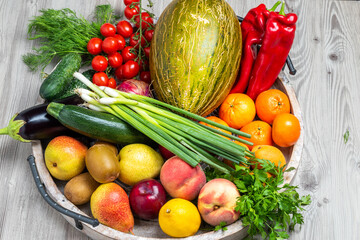 Fruits and vegetables in a wooden tray on grey wooden table background
