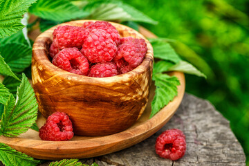 Fresh juicy raspberries in wooden bowl. Summer still life with raspberries on an old wooden table....