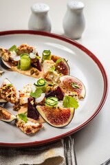 Gourmet salad with ripe figs, goat chevre cheese, fresh cucumber roll, beetroot and mustard leaves with tomato sauce. Summer salad without meat. Delicious and healthy food. Vertical shot