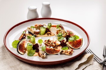 Appetizing gourmet summer salad with ripe figs, goat chevre cheese, fresh cucumber roll, beetroot and mustard leaves with tomato sauce. Summer salad without meat. Delicious and healthy food.