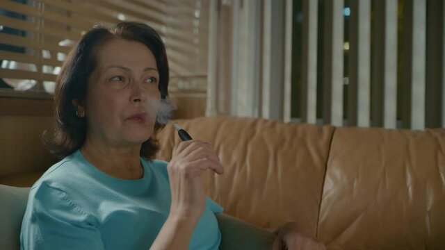 An elderly woman tries to smoke an electronic cigarette for the first time and laughs.