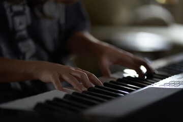 Fototapeta premium The musician's hands on the synthesizer. A cropped image of a person playing a synthesizer. Side view. High quality photo