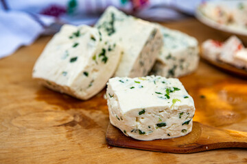 Slice of sheep cheese on a wooden background made from homemade fresh milk.