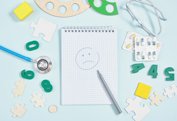 stethoscope, toys, glasses and a notebook with a painted sad face, diagnostics of the psychological state of a child