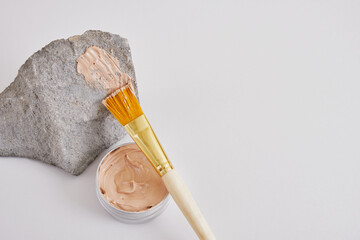 stone, makeup brush and cosmetic red clay in an aluminum jar, natural cosmetics concept
