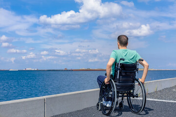 Disabled man in a wheelchair at the sea. Travel, mobility and freedom concept.