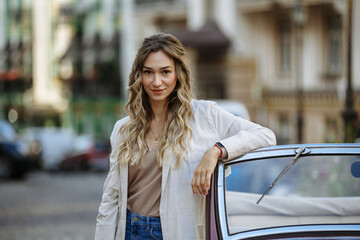 woman in palshche posing against the background of a retro car