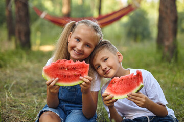 Cute kids eating watermelon in the garden.
