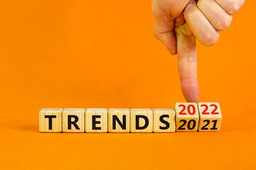 2022 trends new year symbol. Businessman turns wooden cubes and changes words 'Trends 2021' to 'Trends 2022'. Beautiful orange background, copy space. Business, 2022 trends new year concept.