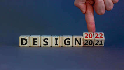 Planning 2022 design new year symbol. Businessman turns wooden cubes and changes words 'design 2021' to 'design 2022'. Beautiful grey background, copy space. Business, 2022 design new year concept.