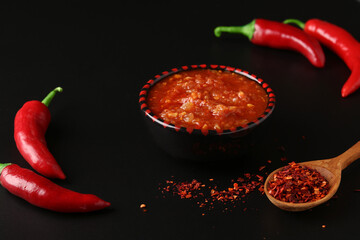 Hot sauce paste harissa with chili pepper on black background, Tunisia and Arabic cuisine