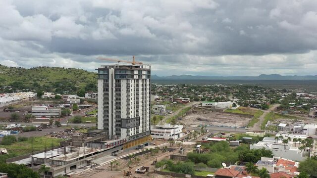 Aerial panoramic view of Hermosillo Sonora, drone flying forward over Lomas de Pitic neighborhood with a cloudy sky as background.