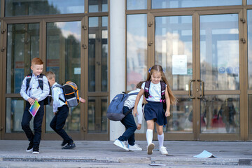 Little schoolchildren run out of the school building