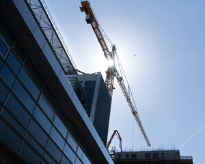 Construction site with tower crane for lifting building materials and the sun in a blue sky