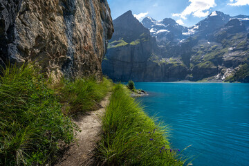 un sentier le long d'une falaise et au dessus d'un lac bleu