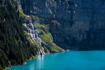 une cascade au bord d'un lac bleu au creux d'une montagne