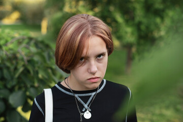 The concept of difficult adolescence in human life. Portrait of a teen girl with a serious, sad...
