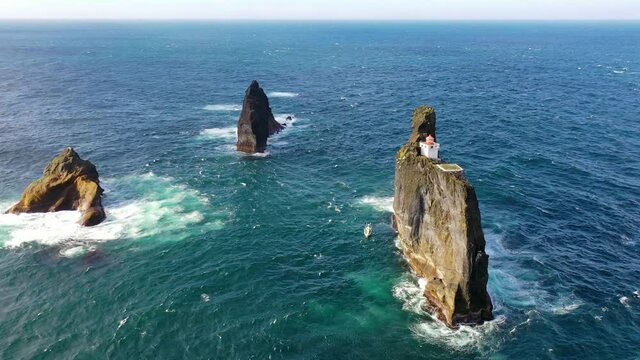 Remarkable aerial of the Pridrangaviti lighthouse perched on a remote rocky island in the Atlantic ocean off the coast of Iceland.