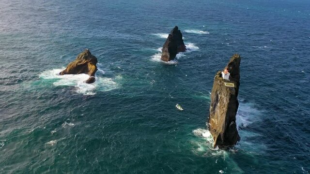 Remarkable aerial of the Pridrangaviti lighthouse perched on a remote rocky island in the Atlantic ocean off the coast of Iceland.