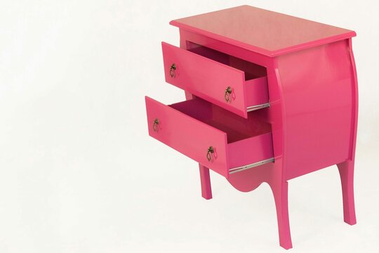Criado mudo de cor rosa com duas gavetas. Moveis cult com um designer moderno e pr&aacute;tico.  Fundo cinza.