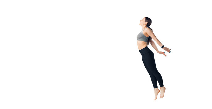 Full length photo of a young woman jumping and stretching at the same time over white background.