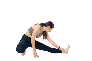 Young woman is warming up her legs while listening to the music in ear pods over white background.