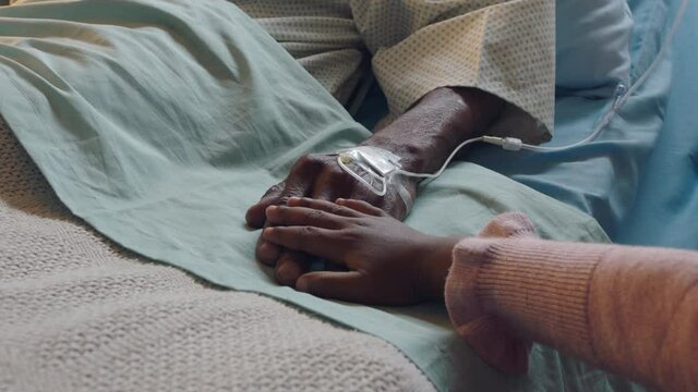little girl touching hand of grandfather lying in hospital bed child showing affection at bedside for grandparent recovering from illness health care family support