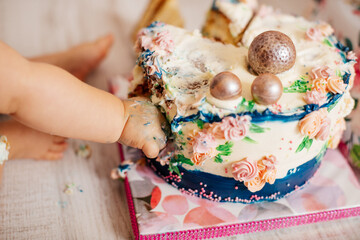 Baby hands in the cake - birthday celebration. First birthday. Happy childish concept