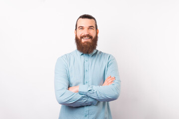 Portrait of a young confident bearded man is smiling at the camera over white background.