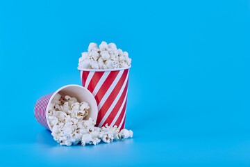 Two full glasses of popcorn on a blue background