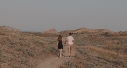 Couple of a man and a girl walking through a field, view from the back