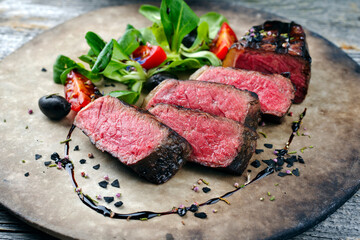 Rustic style barbecue dry aged wagyu roast beef steak with lambs lettuce and tomatoes served as...