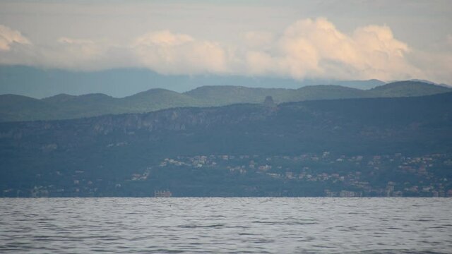 View of Miramare Castle and Temple of Monte Grisa in Italy. Adriatic Sea in the foreground. Small sailing boat sailing on the sea. Beautiful and attractive Italian mountainous coast. Static shot