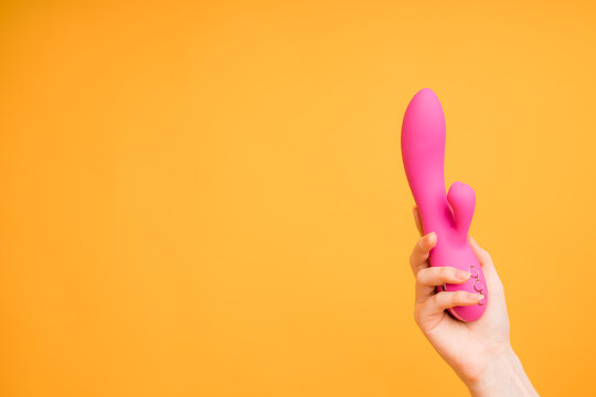 A pink dildo lies in the girl's hand with a massager for the clitoris. Useful for a sex shop