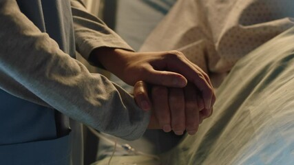 hospital nurse holding hand of old woman in bed comforting elderly patient sleeping recovering from illness medical professional at bedside giving encouragement health care support