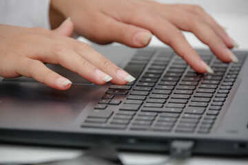 hand on the black keyboard of a computer typing text.
