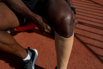 Male knee of an African American with a sports stocking on the shin