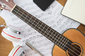 Fototapeta premium Wooden guitar headphones and music notes on table closeup