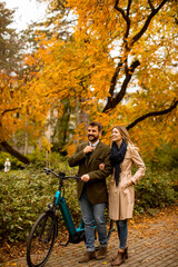 Young couple in the autumn park with electrical bicycle