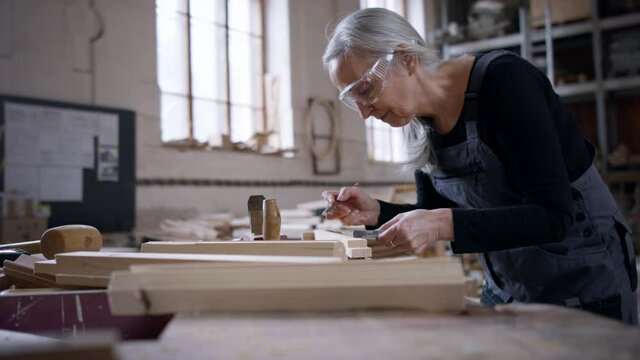 Senior female carpenter working on her product. Small business concept.
