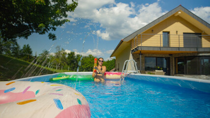 CLOSE UP: Joyful Caucasian female is enjoying the summertime in her home pool.