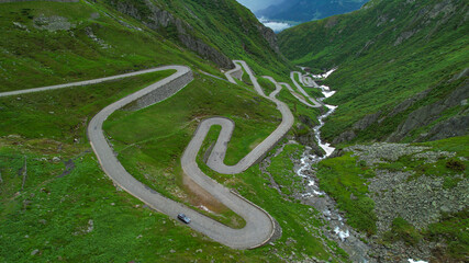 DRONE: Tourists on fun road trip across Switzerland drive along Gotthardpass.